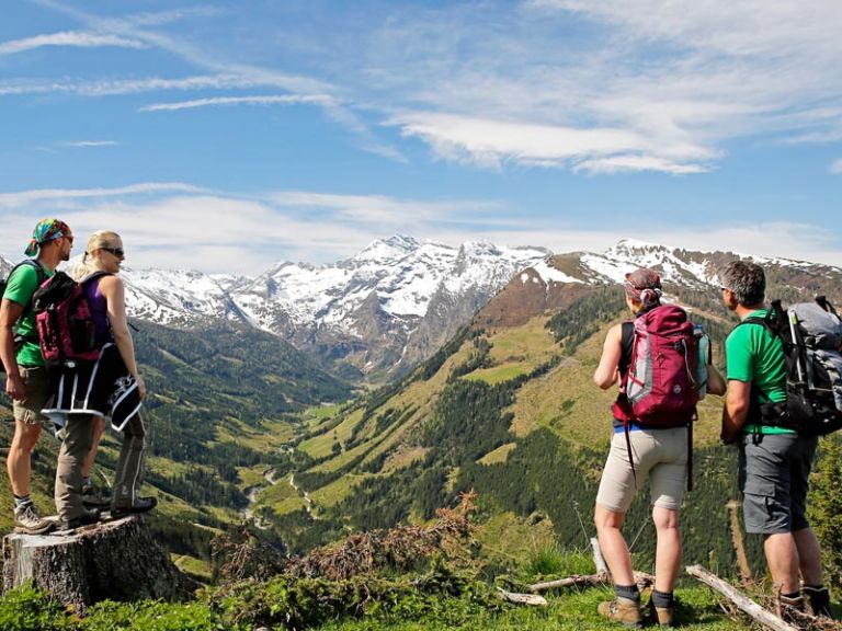 4 Menschen stehen am Gipfel eines Berges und bestaunen die Natur